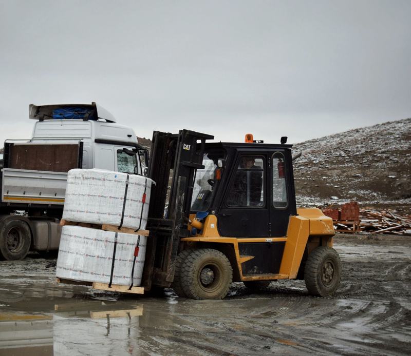 Forklift moving a pallet at an outdoor industrial yard in winter
